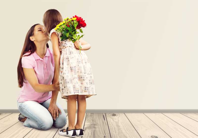 手拿鲜花的小女孩在亲吻妈妈