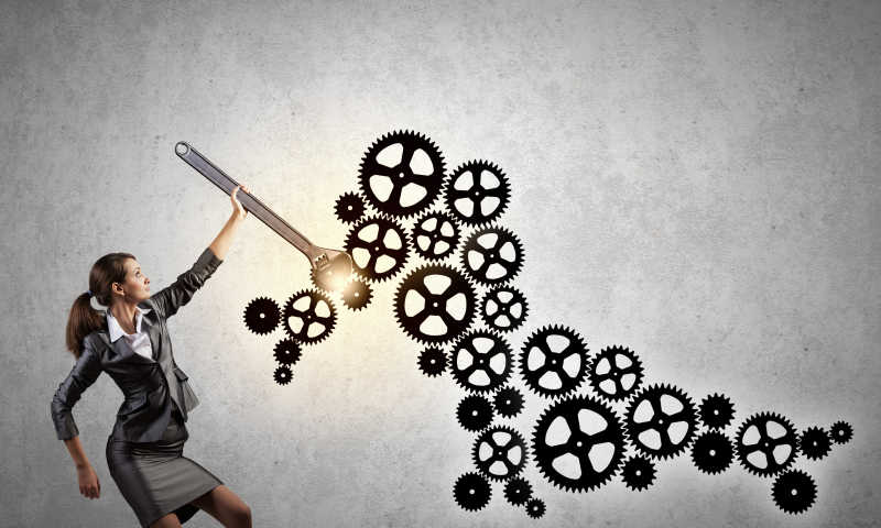 年轻女商人用扳手在固定齿轮机构