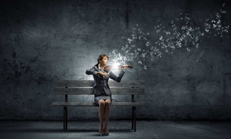 坐在板凳上拉小提琴的年轻女子