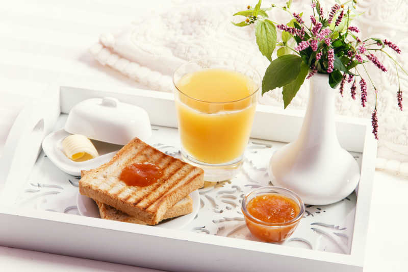 床上木托盘上的饮料和美食