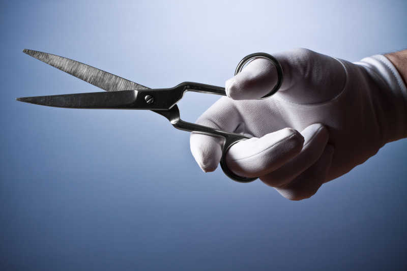 带着白色手套的手拿着剪刀