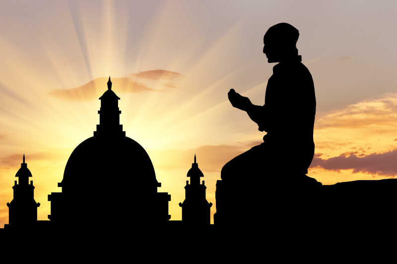 日落时分祈祷的男人剪影和清真寺