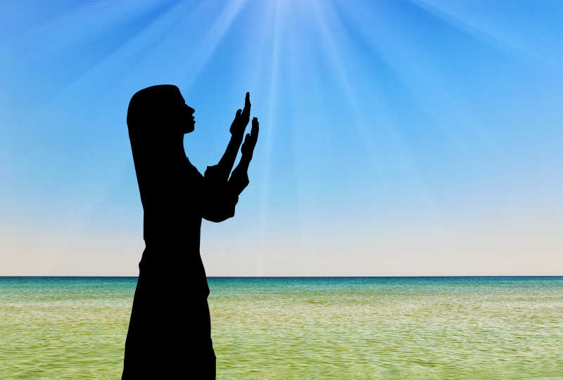 海边阳光下祈祷妇女