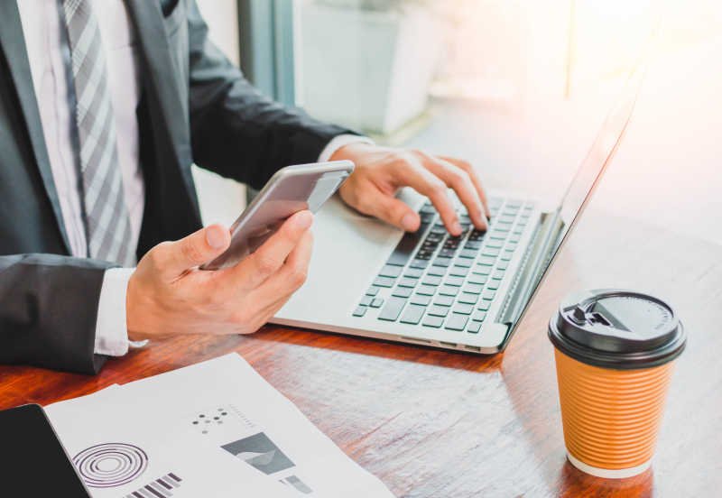 商人手中的手机与笔记本电脑