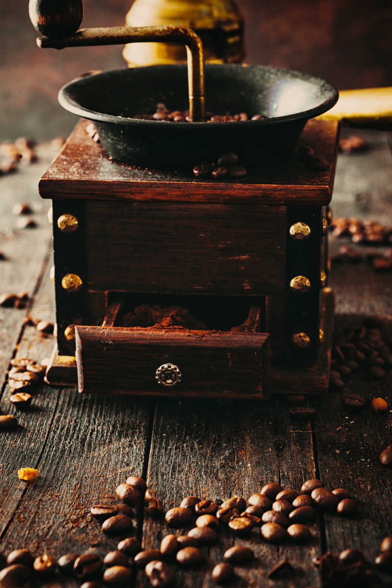 木桌上放着磨咖啡豆的机器和咖啡豆