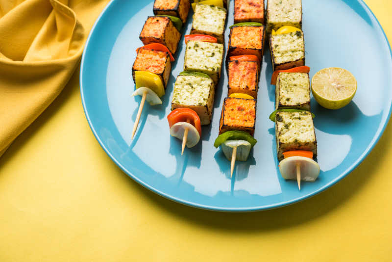 黄色背景下蓝色盘子里的蔬菜烧烤