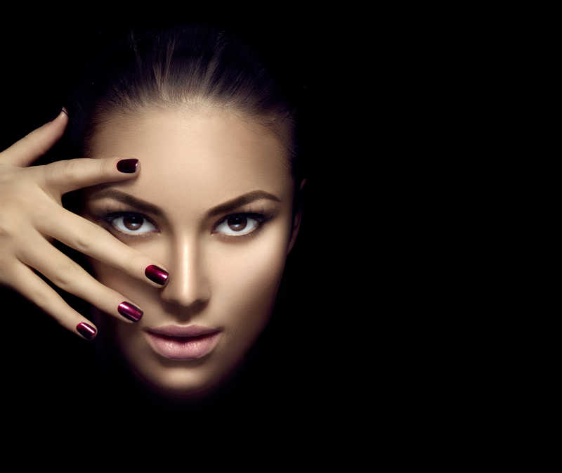 黑色背景下美女的手和脸