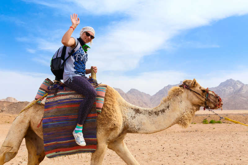 沙漠中骑骆驼的年轻女人