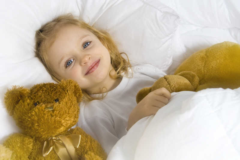 抱着娃娃躺在床上的小女孩
