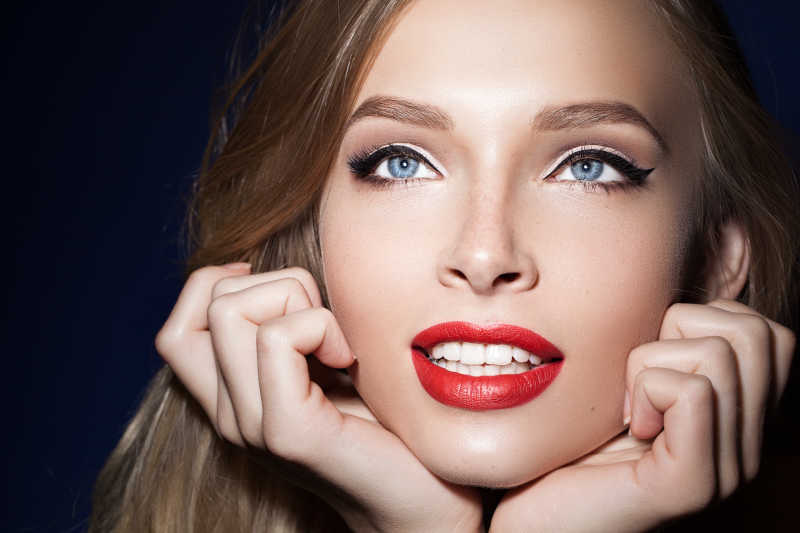 红色嘴唇的美女用手托着下巴