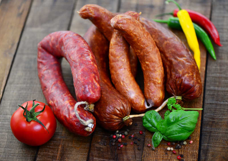 砧板上放有香肠辣椒与番茄