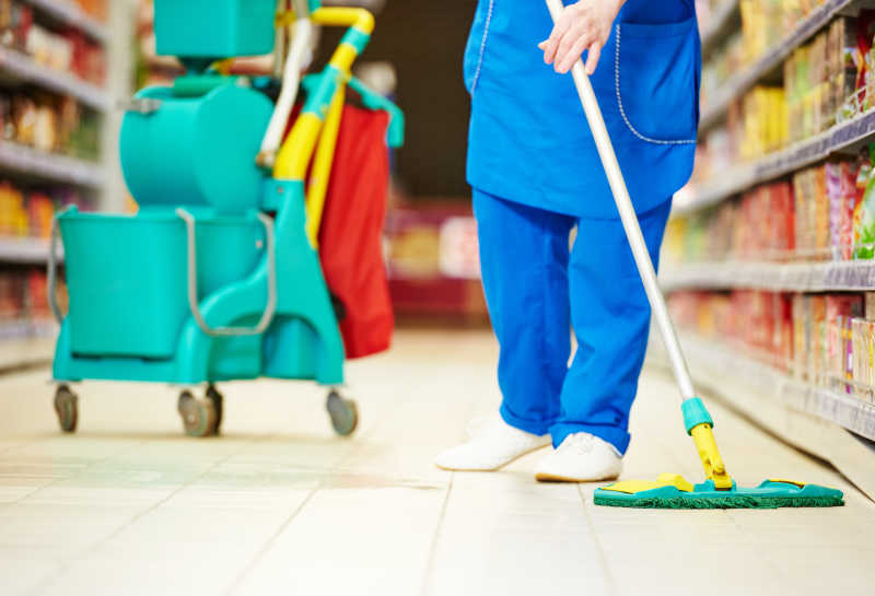 女清洁工用拖把打扫超市商店的地板