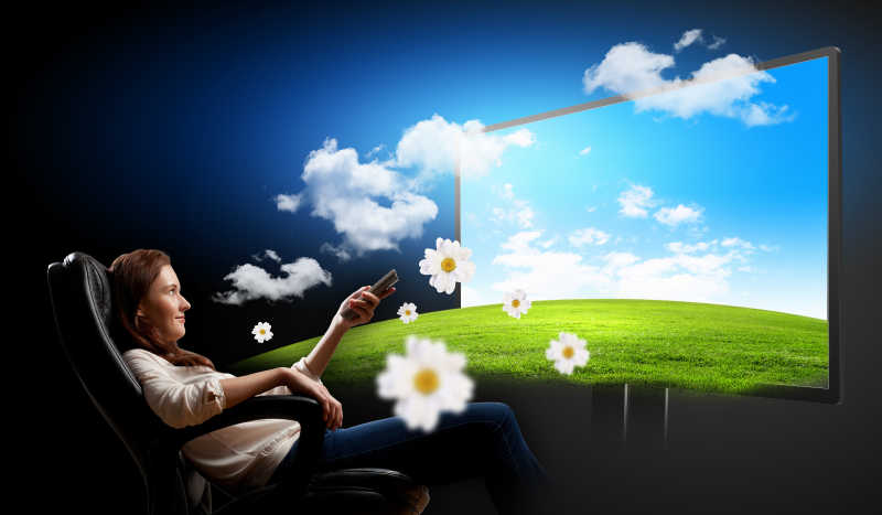 坐在扶手椅上看3D电视的年轻女子形象