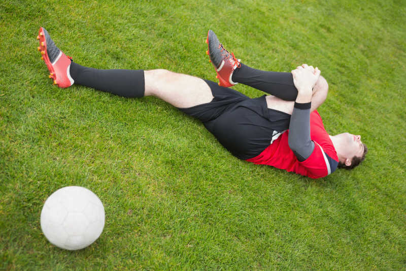 足球运动员在晴朗的日子里躺在球场上受伤