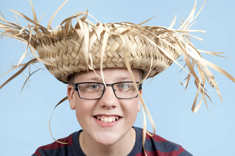 蓝色背景下戴着草帽的少年