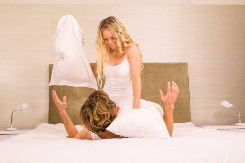 情侣手拿枕头在床上打架