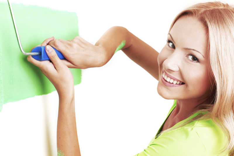 白色背景下拿着滚动刷的微笑美女