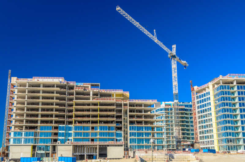 蓝天下正在施工的高层建筑和起重机