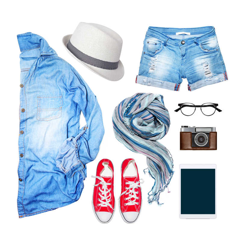 白色背景下的牛仔短裤衬衫帆布鞋帽子围巾眼镜手机和照相机