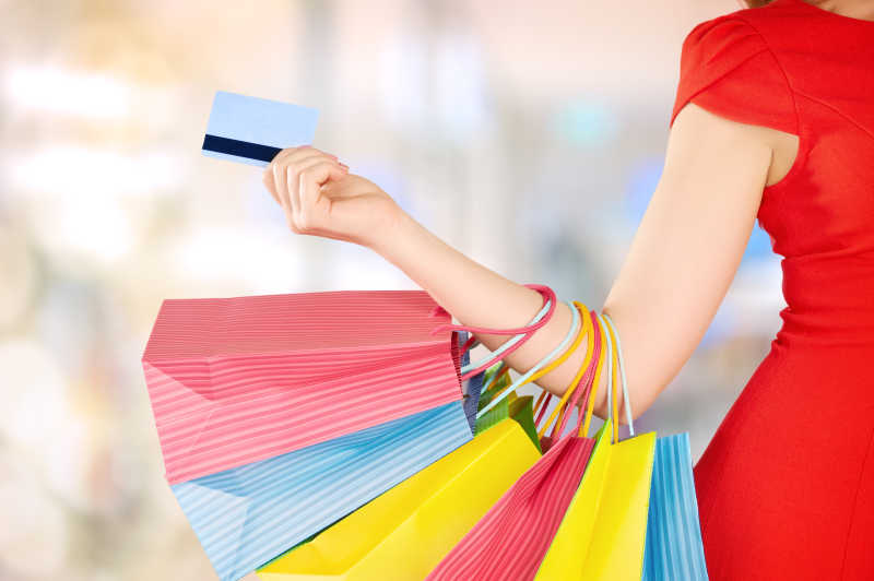 拿着信用卡拎着购物袋的美女