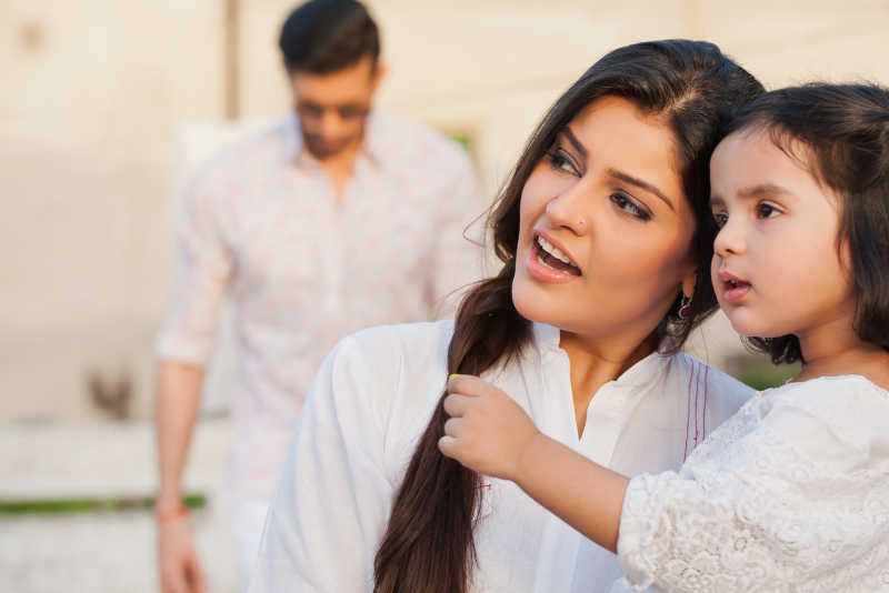 虚化的爸爸背景和抱着女儿的妈妈
