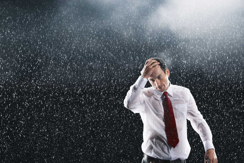 黑色背景上淋雨的商人