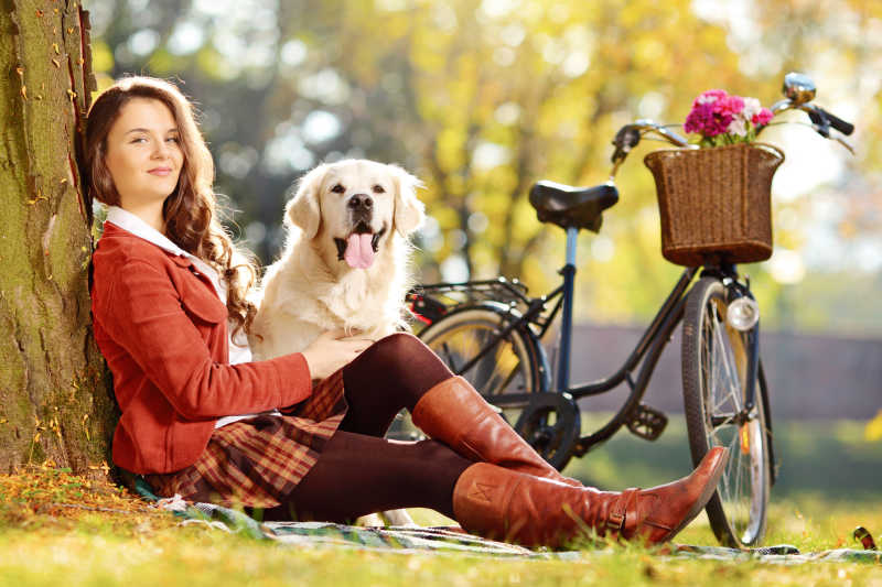 坐在树下的美女和可爱的拉布拉多犬
