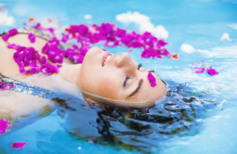 洒满花瓣的泳池里泡澡的美女