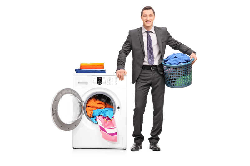穿着西装的商人手持装满衣服的洗衣篮与装有衣服的洗衣机