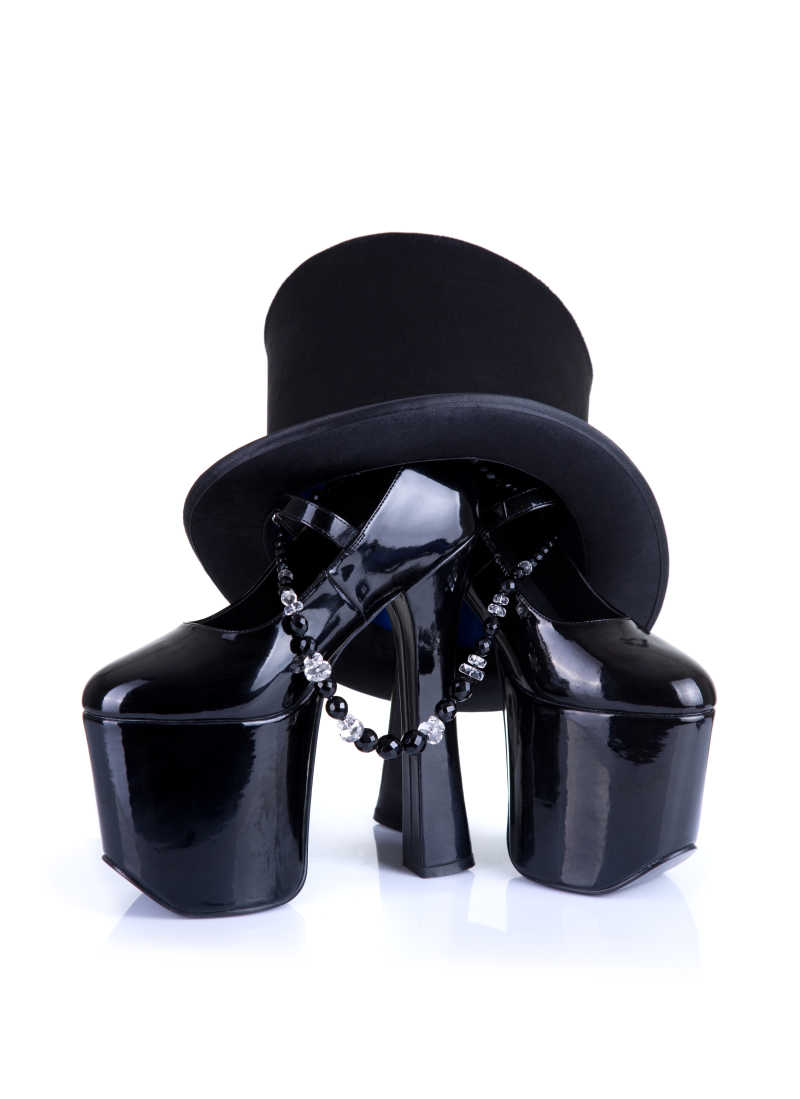 白色背景下的黑色高跟鞋珠串项链和黑色礼帽