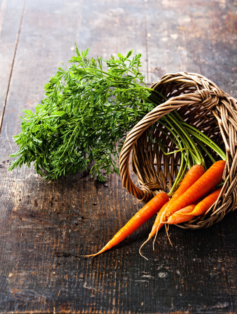 新鲜的胡萝卜放在木制背景的篮子里