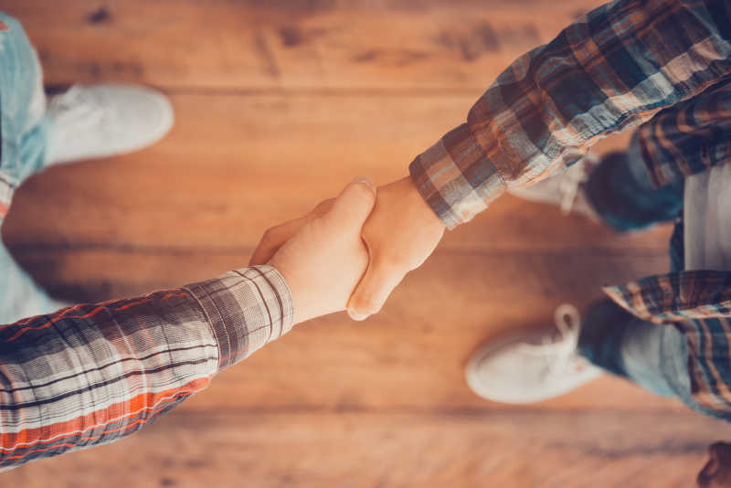 两个男人站在木地板上握手