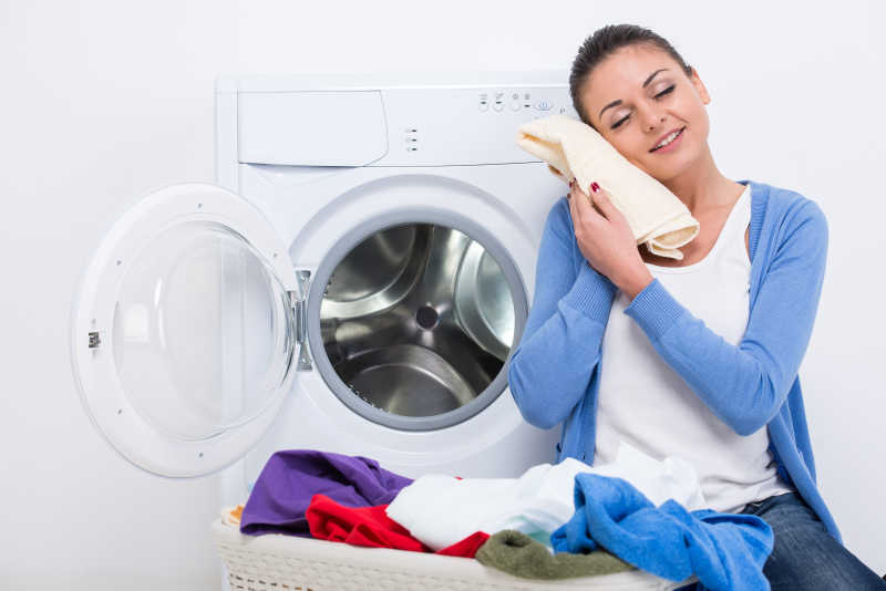 年轻的主妇正在洗衣机前整理衣物