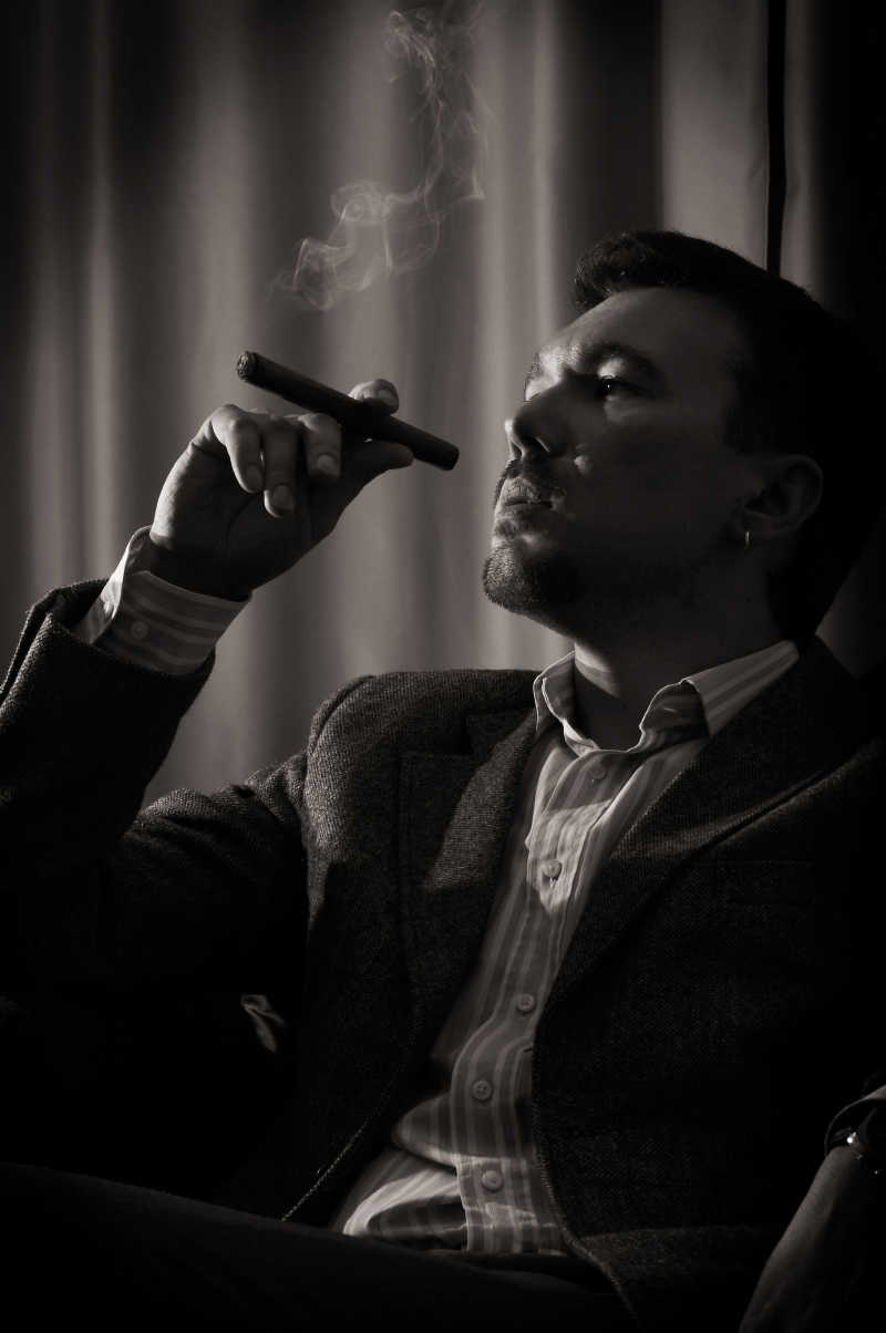 黑暗环境里的抽雪茄的忧郁男人