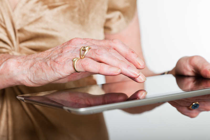 一位年长妇女使用平板电脑的手