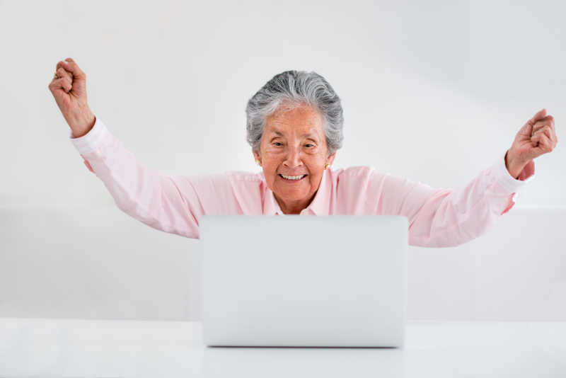 对着电脑双臂庆祝的年长妇女