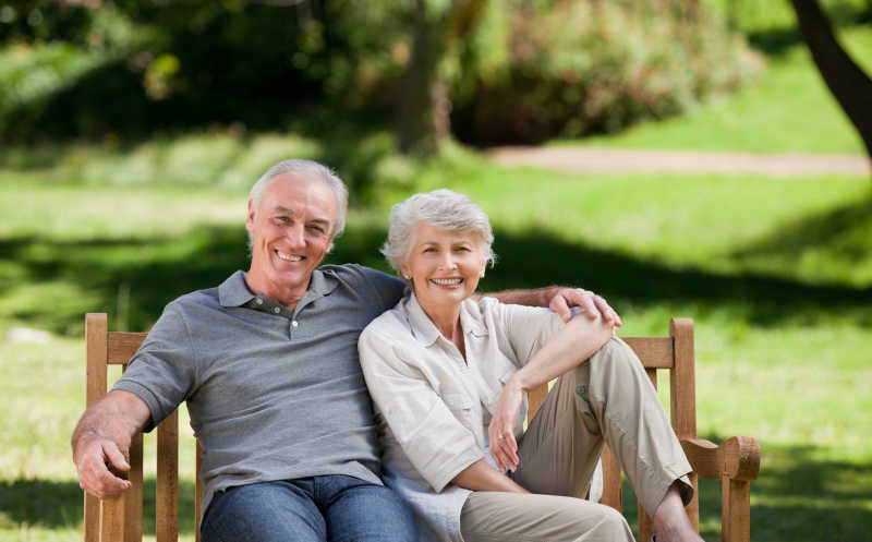 面带微笑坐在长椅上的老夫妇