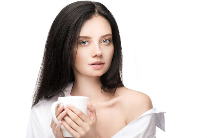 白衬衣黑发美女手拿白色水杯