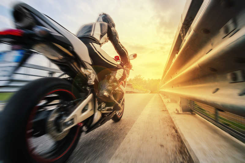 飞驰摩托车道路护栏旁的日落