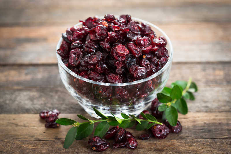 木质桌面上玻璃碗里的小红莓干