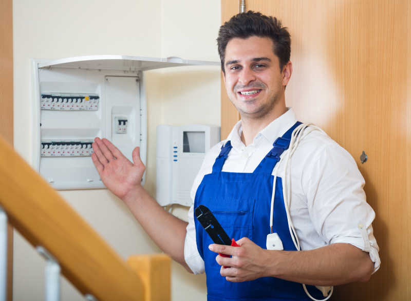 电工微笑着检查展示家用电器自动控制屏