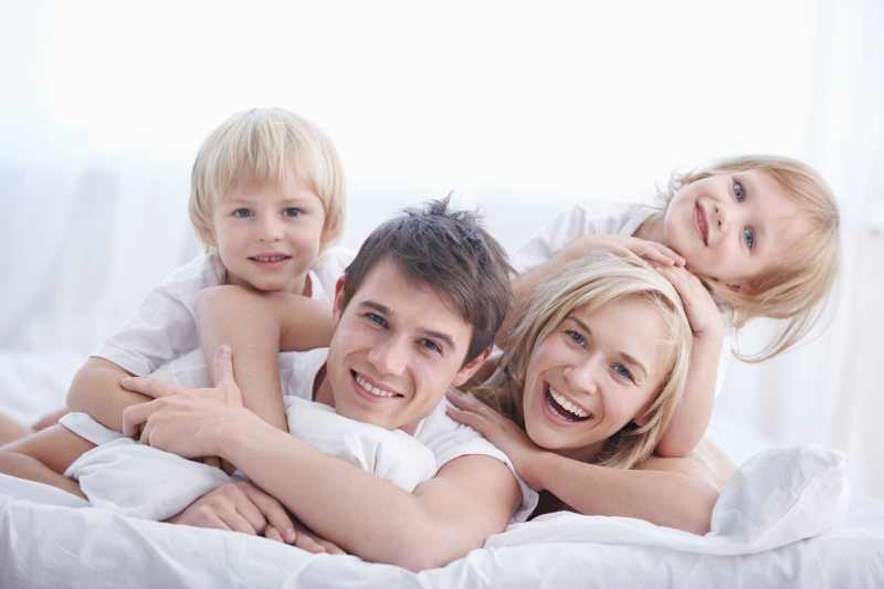 卧室白色床上的幸福快乐的家庭