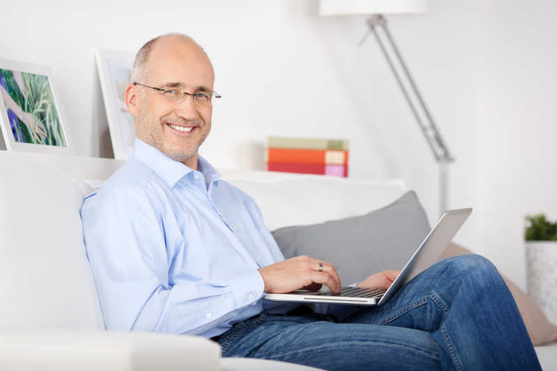 坐在沙发上浏览互联网的快乐的男人
