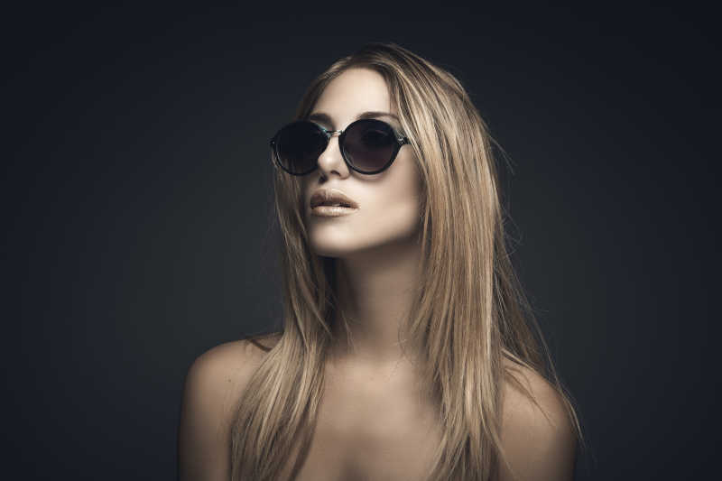 黑色背景下带着墨镜的金发美女