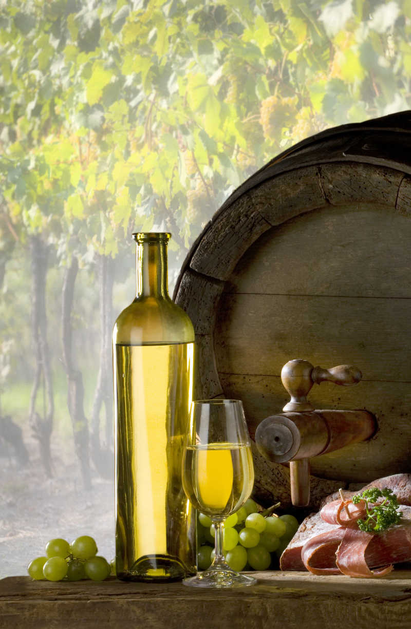 桌上的葡萄和盛葡萄酒的木桶杯子以及瓶子