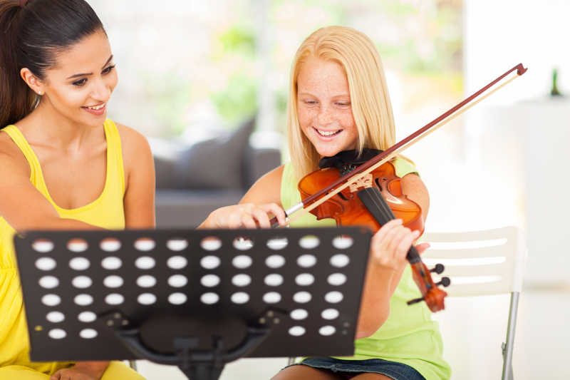 微笑女孩和老师一起练习小提琴