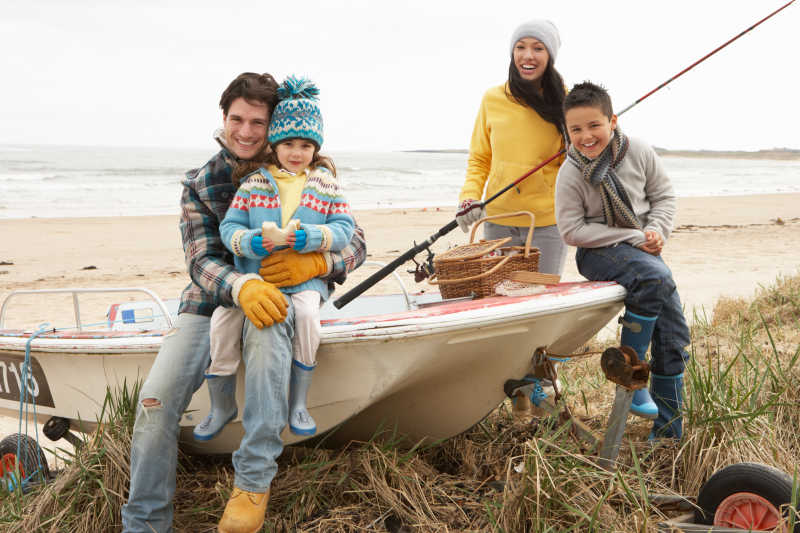 冬季坐在船边钓鱼的一组家庭