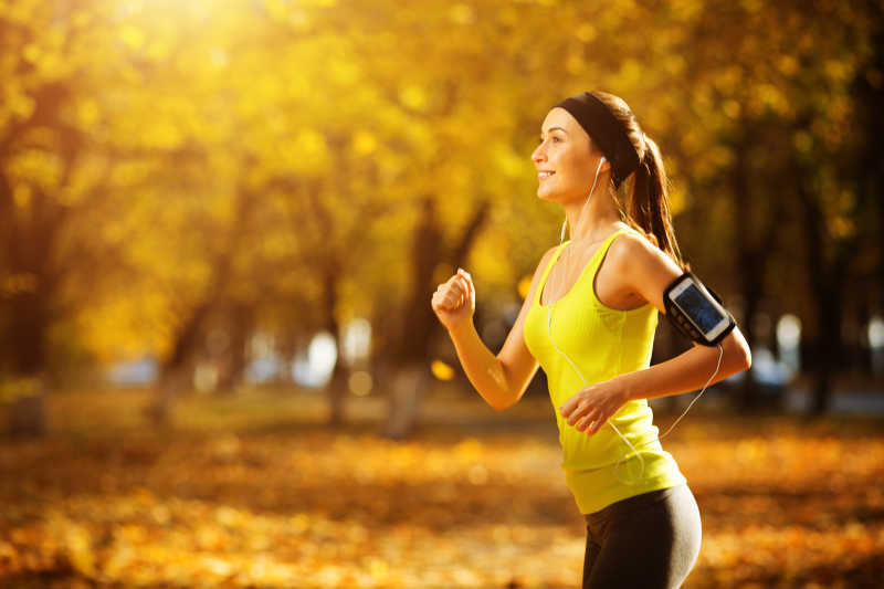 温暖的秋日在跑步的一个年轻女人