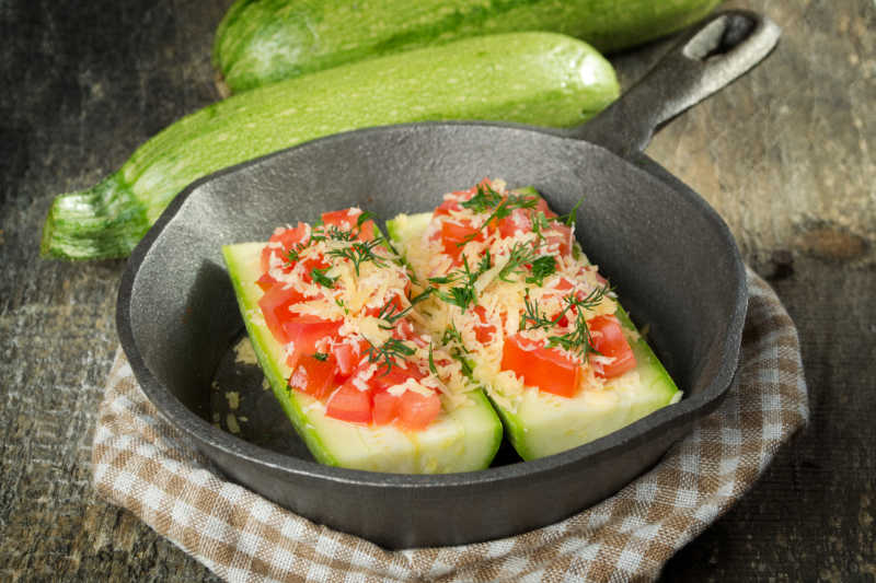 锅里的西葫芦上的番茄和奶酪