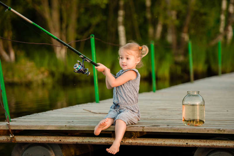 河流码头上钓鱼的小女孩